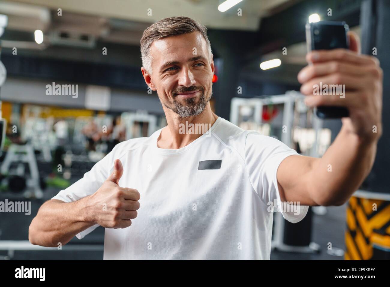 Attractive confident young man taking selfie while standing in the gym Stock Photo