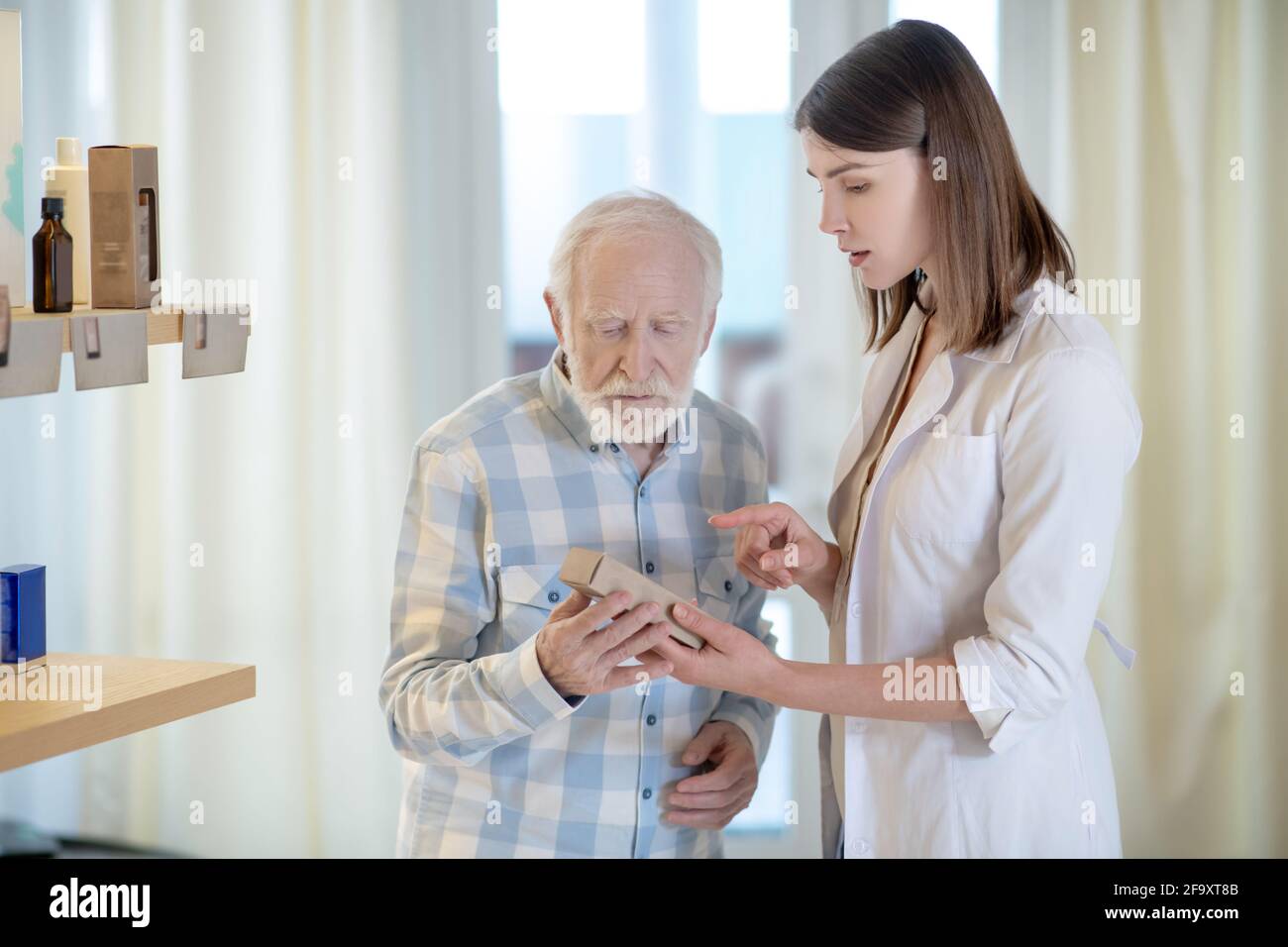 Shop assistant helping an old man choose the body care products Stock Photo