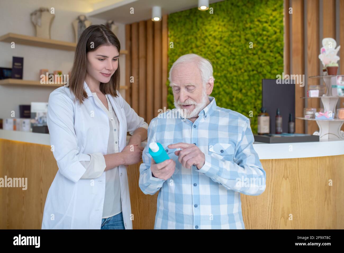 Shop assistant helping an old man choose the body care products Stock Photo