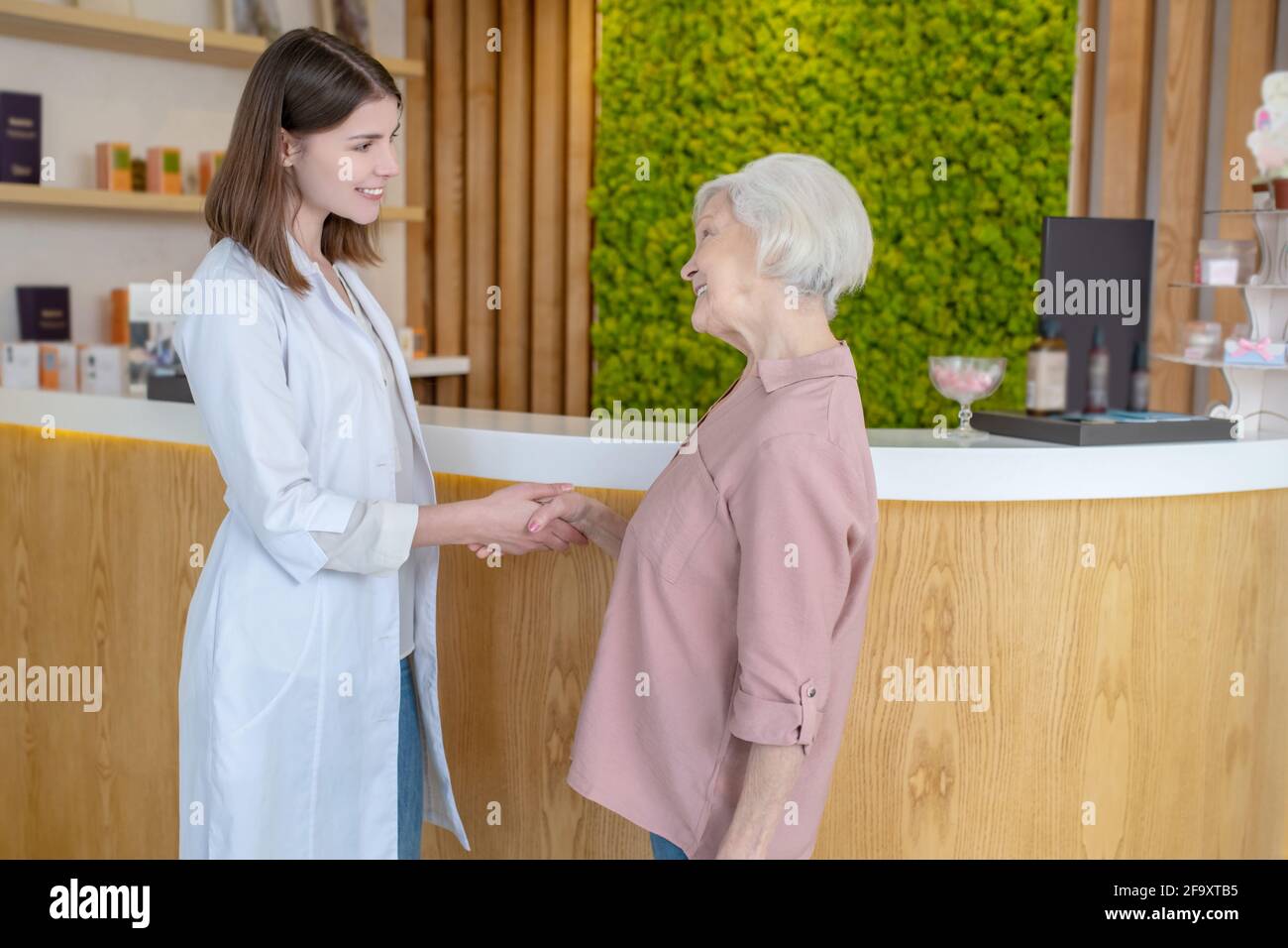 Pretty young cosmetologist greeting a mature customer Stock Photo