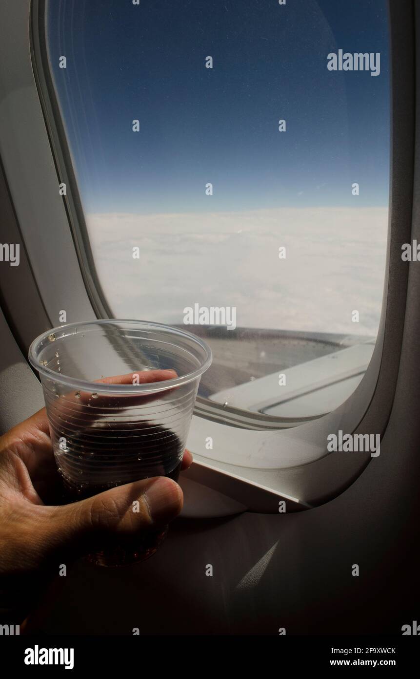 looking out the window of an airplane having a glass of soda, from the