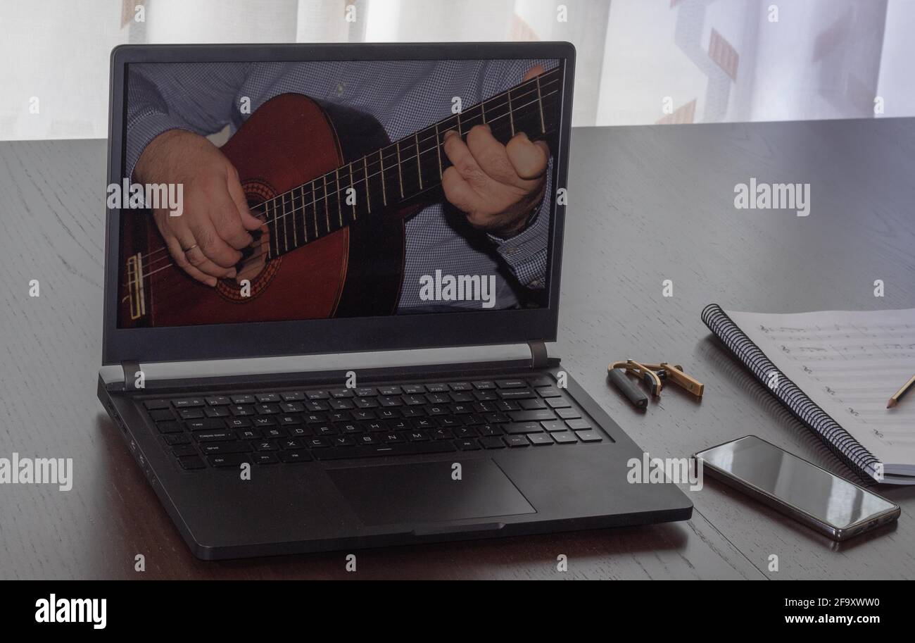 watching video of the online spanish guitar course at home with the laptop, during covid-19 confinement Stock Photo