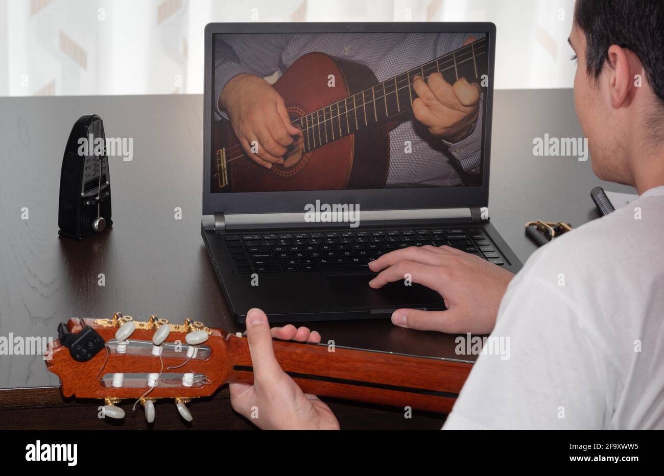 young person doing and consulting the online spanish guitar course at home,  with the metronome and laptop, during the confinement of the covid-19 Stock  Photo - Alamy
