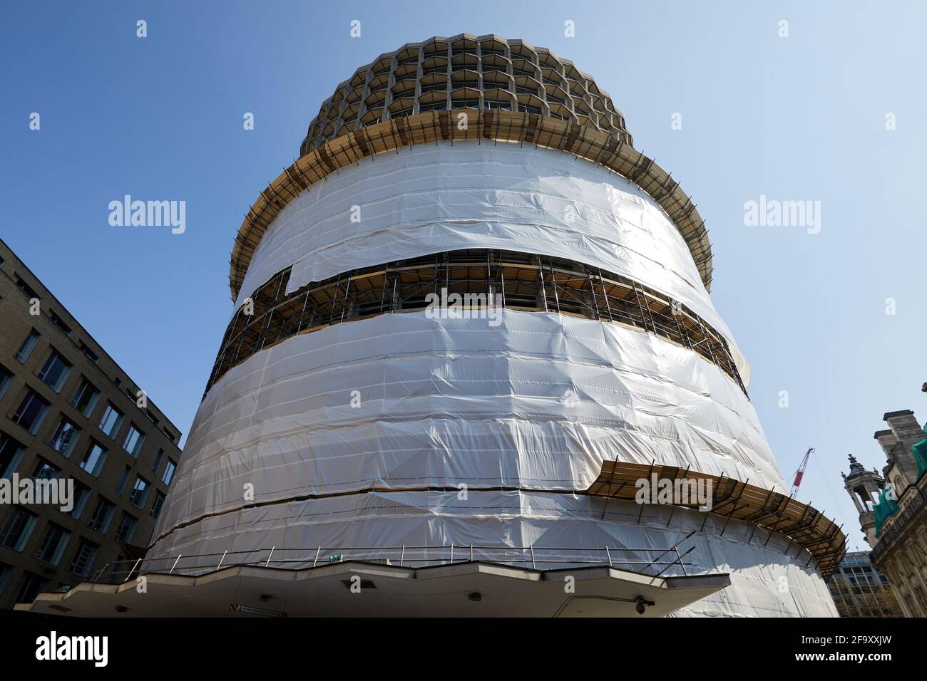 London, UK - 20 Apr 2021:  Space House, a 17-storey cylindrical  office tower in the Holborn area, partially wrapped in protective sheeting. Stock Photo