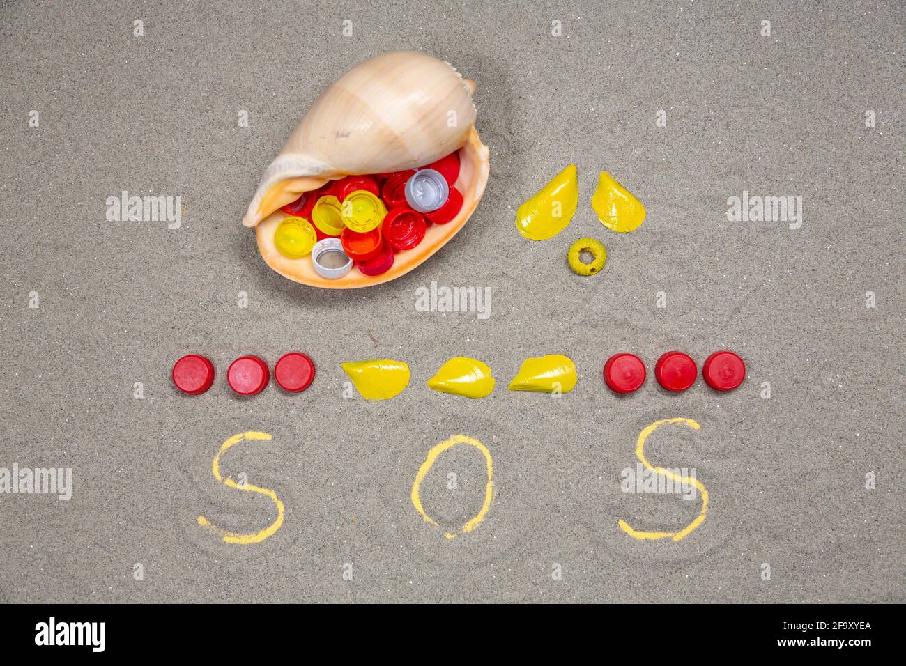 SOS made of PET plastic bottle plugs and seashells. Nature pollution ...