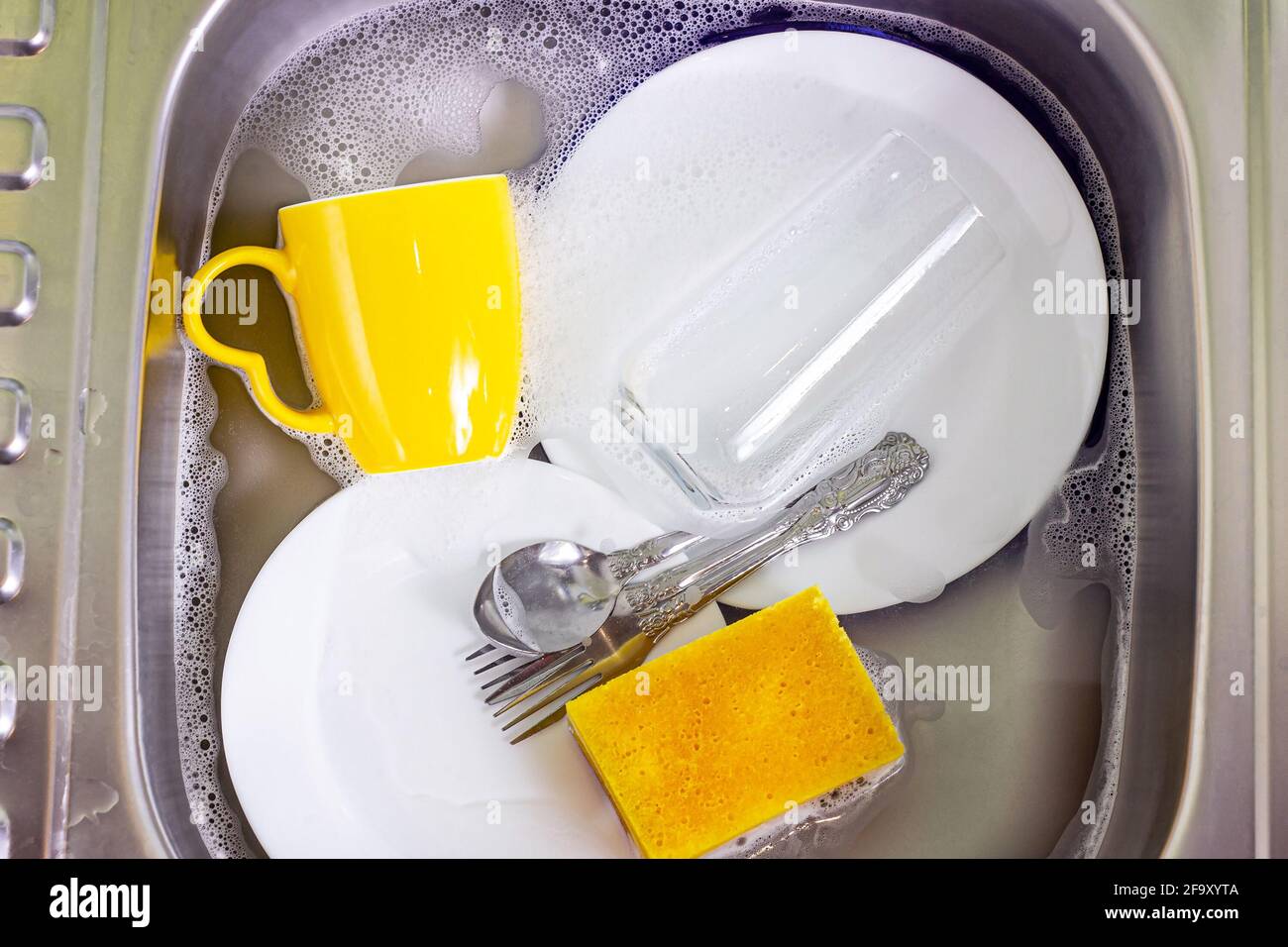 Metal sink in the kitchen full of dirty dishware stack. Housework, washing dishes, household duties concept. Stock Photo