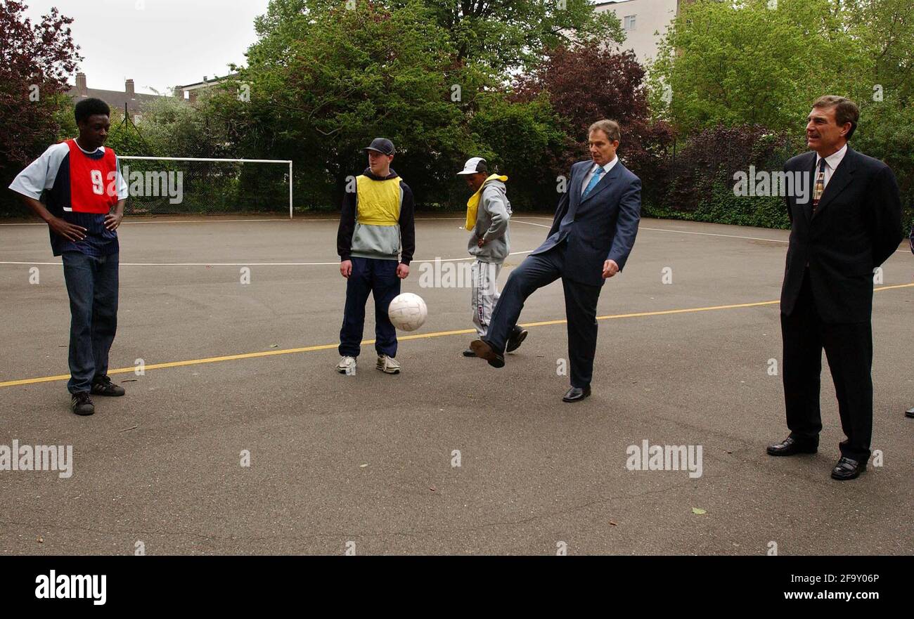 TONY BLAIR AND TREVOR BROOKING KICK A BALL ABOUT WITH YOUTHS AT NEWINGTON GARDENS FOOTBALL PITCH IN SE1.9/5/02 PILSTON Stock Photo
