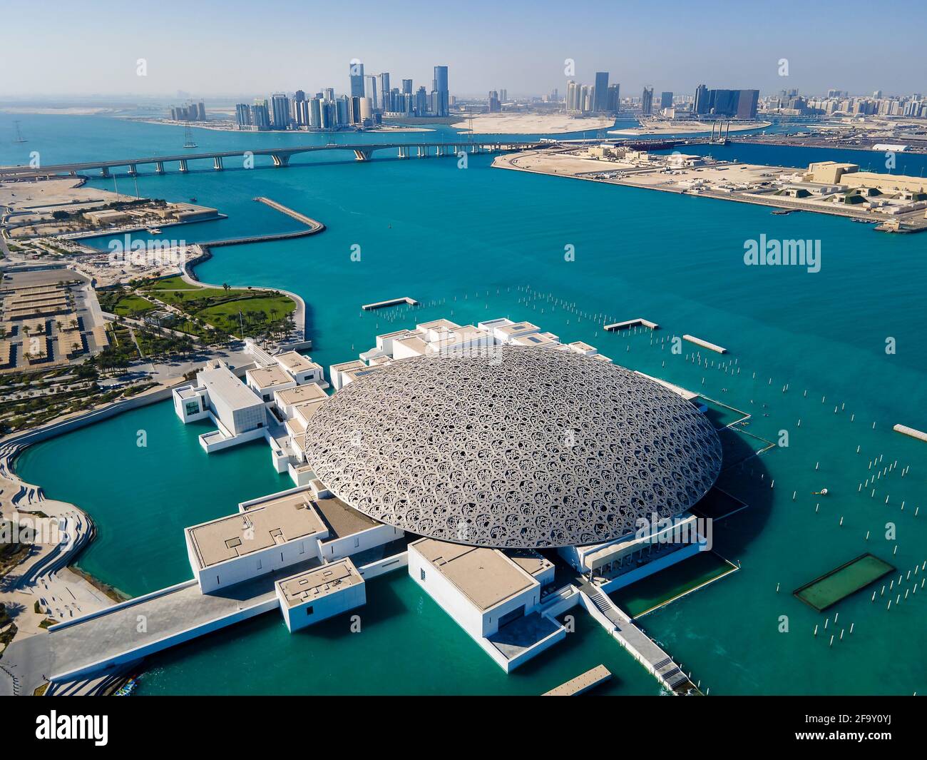 Abu Dhabi, United Arab Emirates - April 6, 2021: Louvre museum and Abu Dhabi aerial cityscape rising from the seaside water at the United Arab Emirate Stock Photo