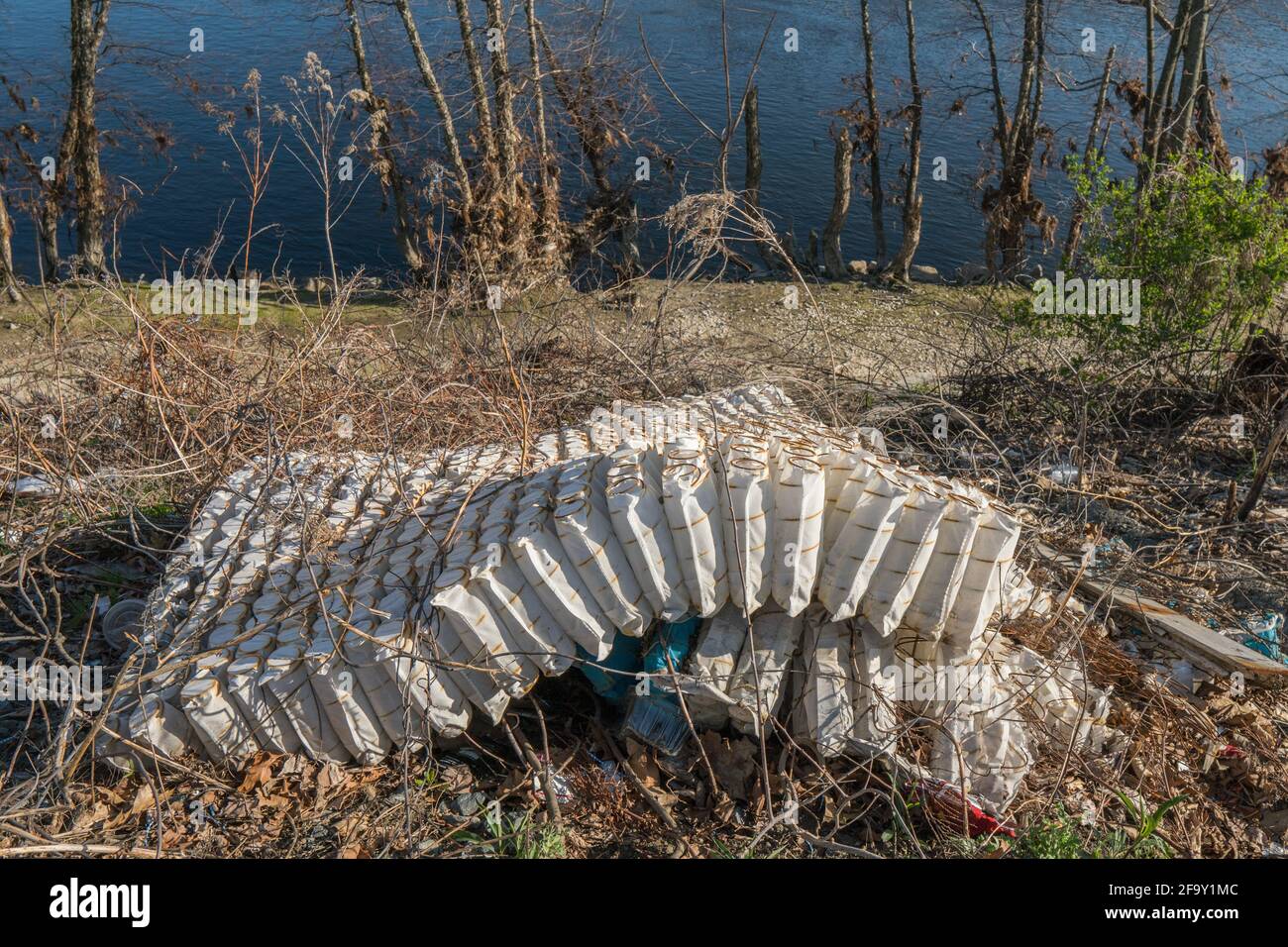 Old mattress dumped illegally in urban area. Stock Photo