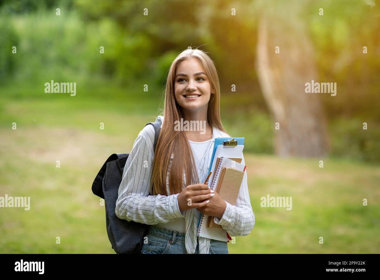 Freshman Girl. Beautiful Female College Student With Workbooks And Backpack Posing Outdoors Stock Photo