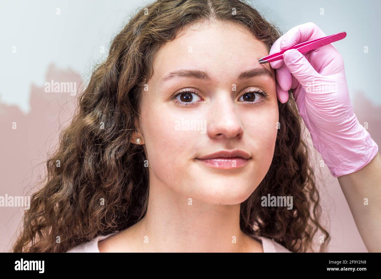 eyebrow master makes an eyebrow correction to a young woman. Henna