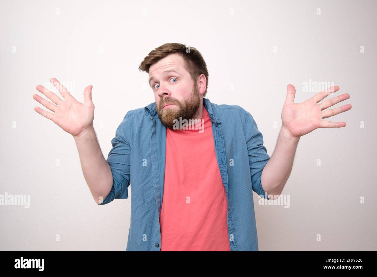 Surprised bearded man in bewilderment, he is innocent and makes a gesture with hands, open palms, looks at the camera.  Stock Photo