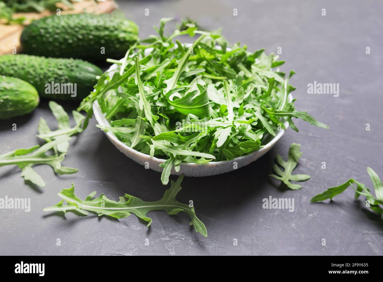 Fresh arugula leaves in bowl on dark table.Fresh vegeterian food concept Stock Photo