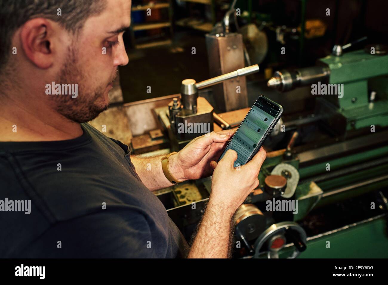 Closeup shot of a Hispanic mechanical engineer texting on the phone Stock Photo