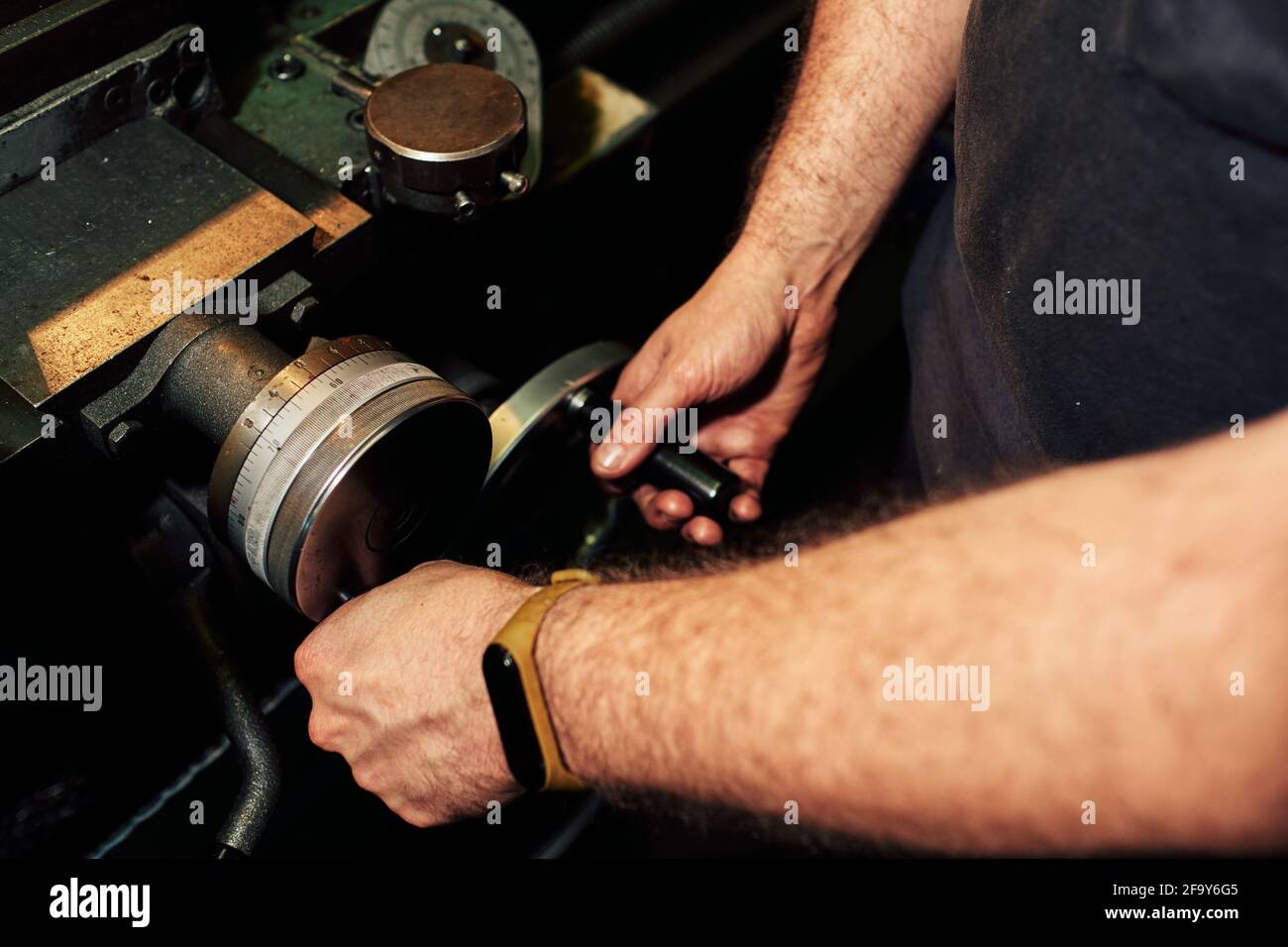 Closeup shot of a Hispanic mechanical engineer controlling the lathe machine in a factory Stock Photo