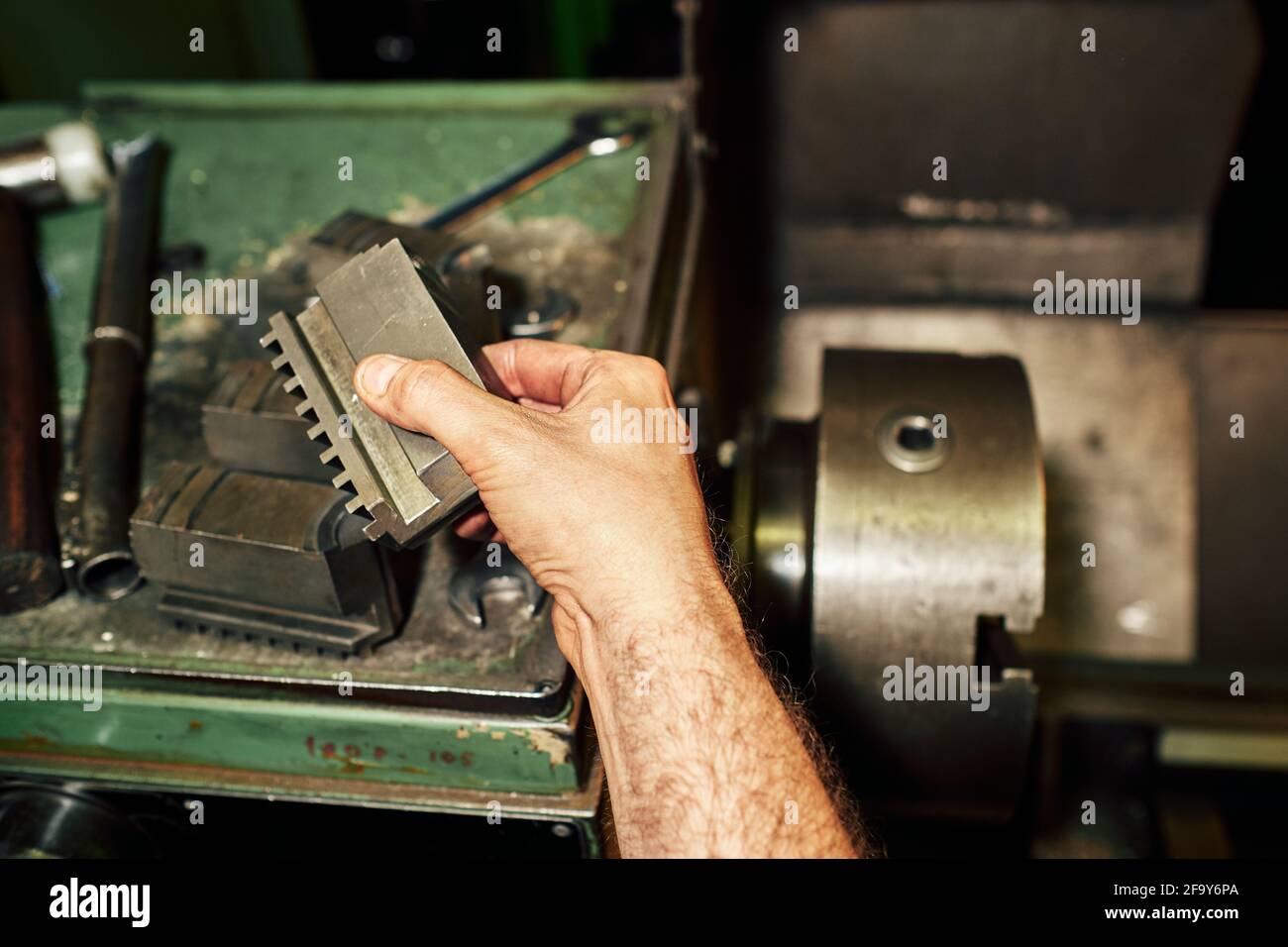 Closeup shot of a Hispanic mechanical engineer controlling the lathe machine in a factory Stock Photo