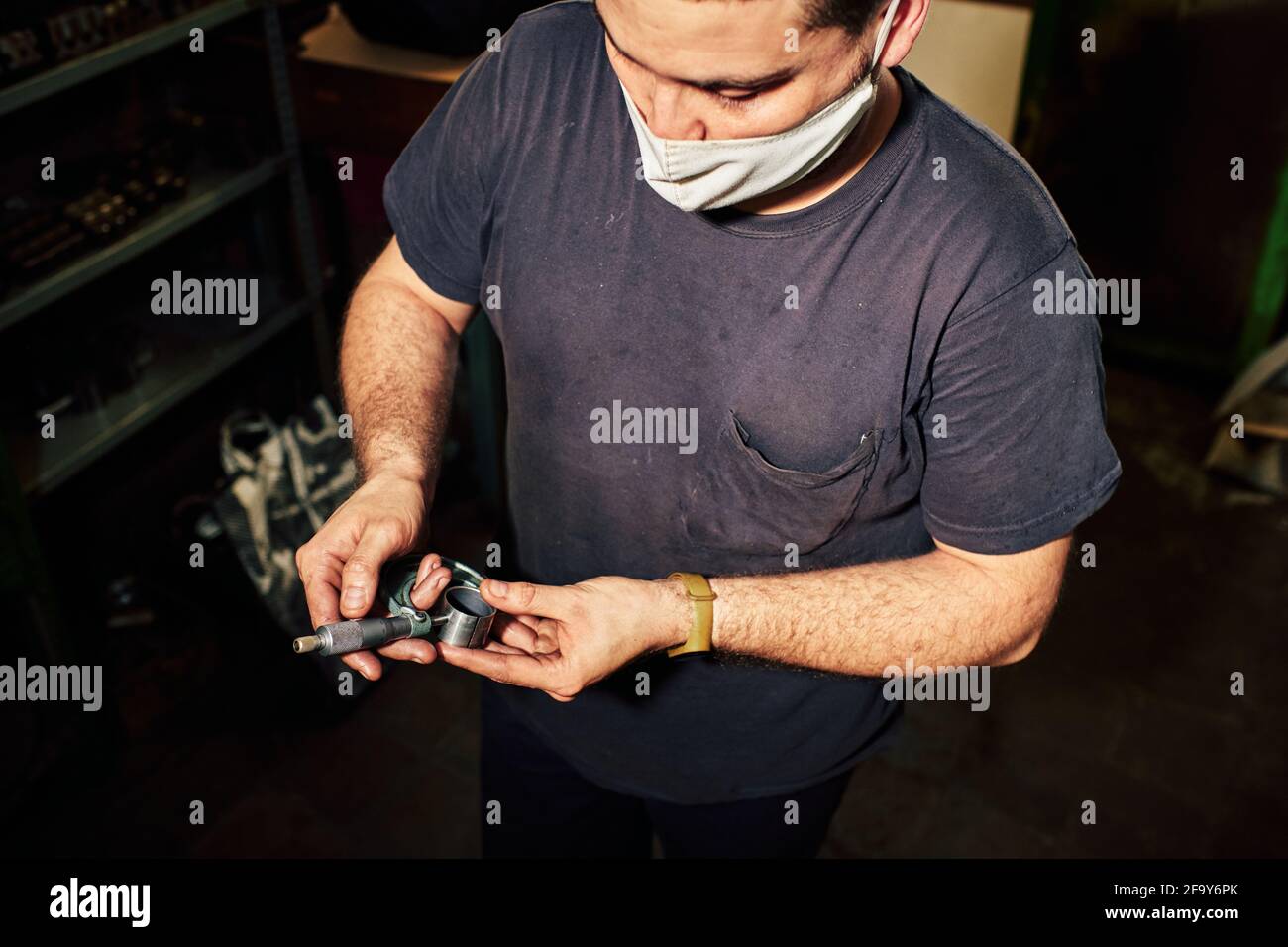 Closeup shot of a Hispanic mechanical engineer controlling the lathe machine in a factory Stock Photo