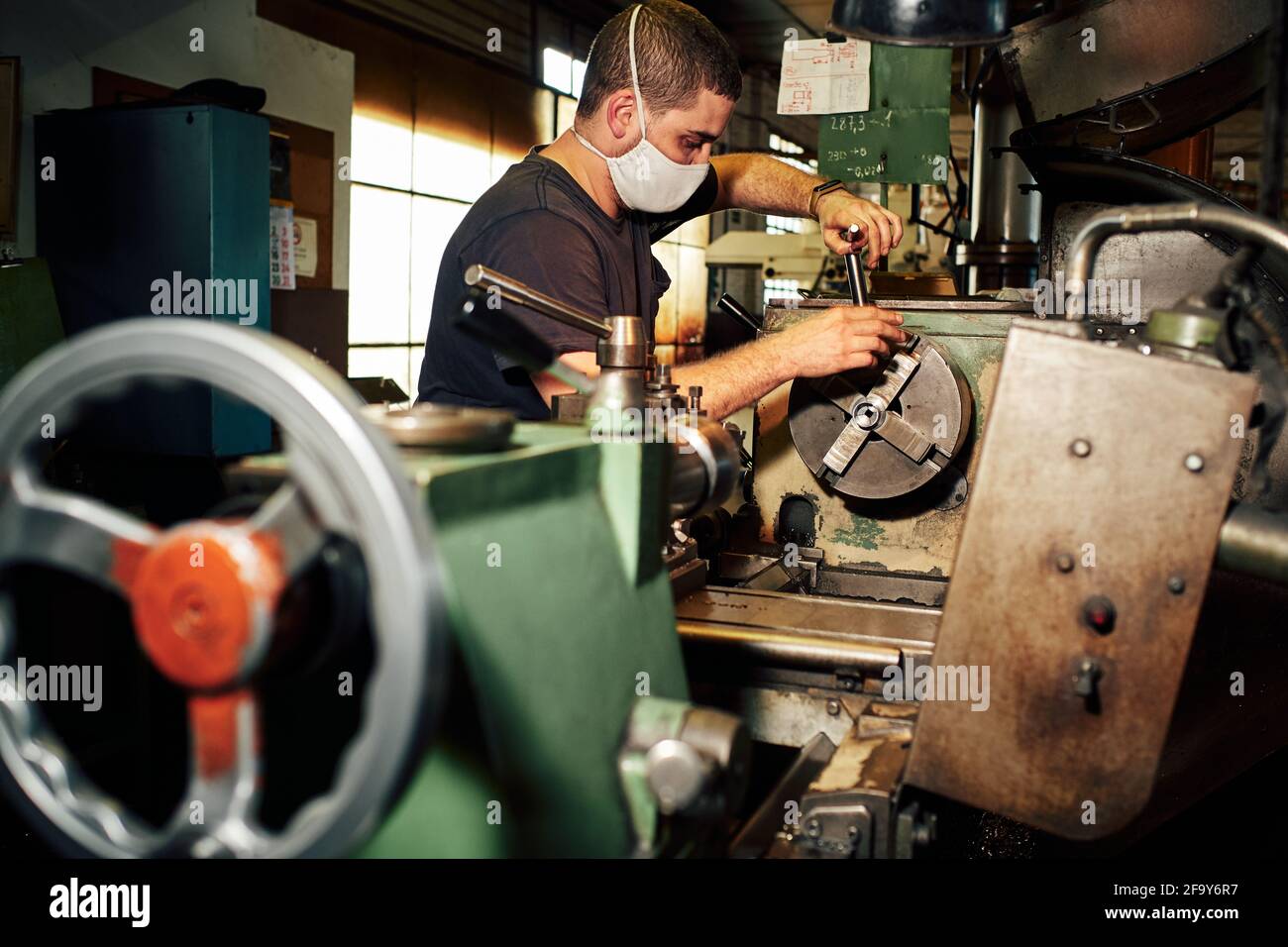 Closeup shot of a Hispanic mechanical engineer controlling the lathe machine in a factory Stock Photo