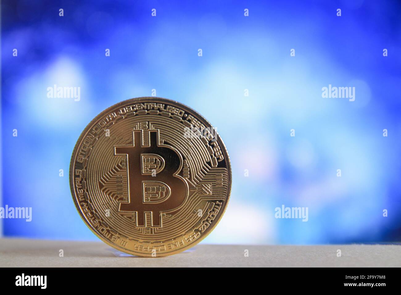 A physical version of Bitcoin BTC with blurred blue background. Stock Photo