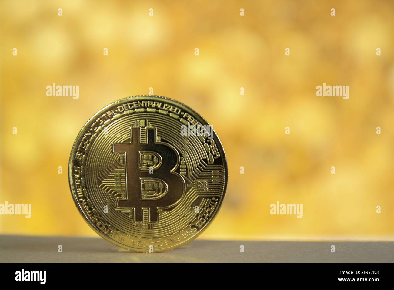 A physical version of Bitcoin BTC with blurred golden background . Stock Photo