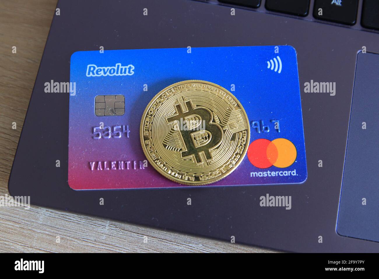 Berlin, Germany - April 21, 2021: Revolut Mastercard and a bitcoin currency lying on laptop.Revolut is a fast, simple, and easy way to buy, sell, and Stock Photo