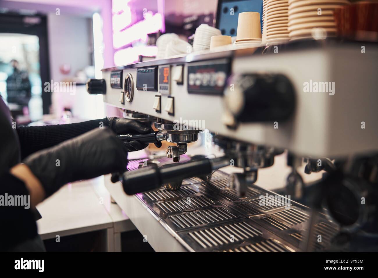 Busy barista operating a modern coffee machine at cafe Stock Photo