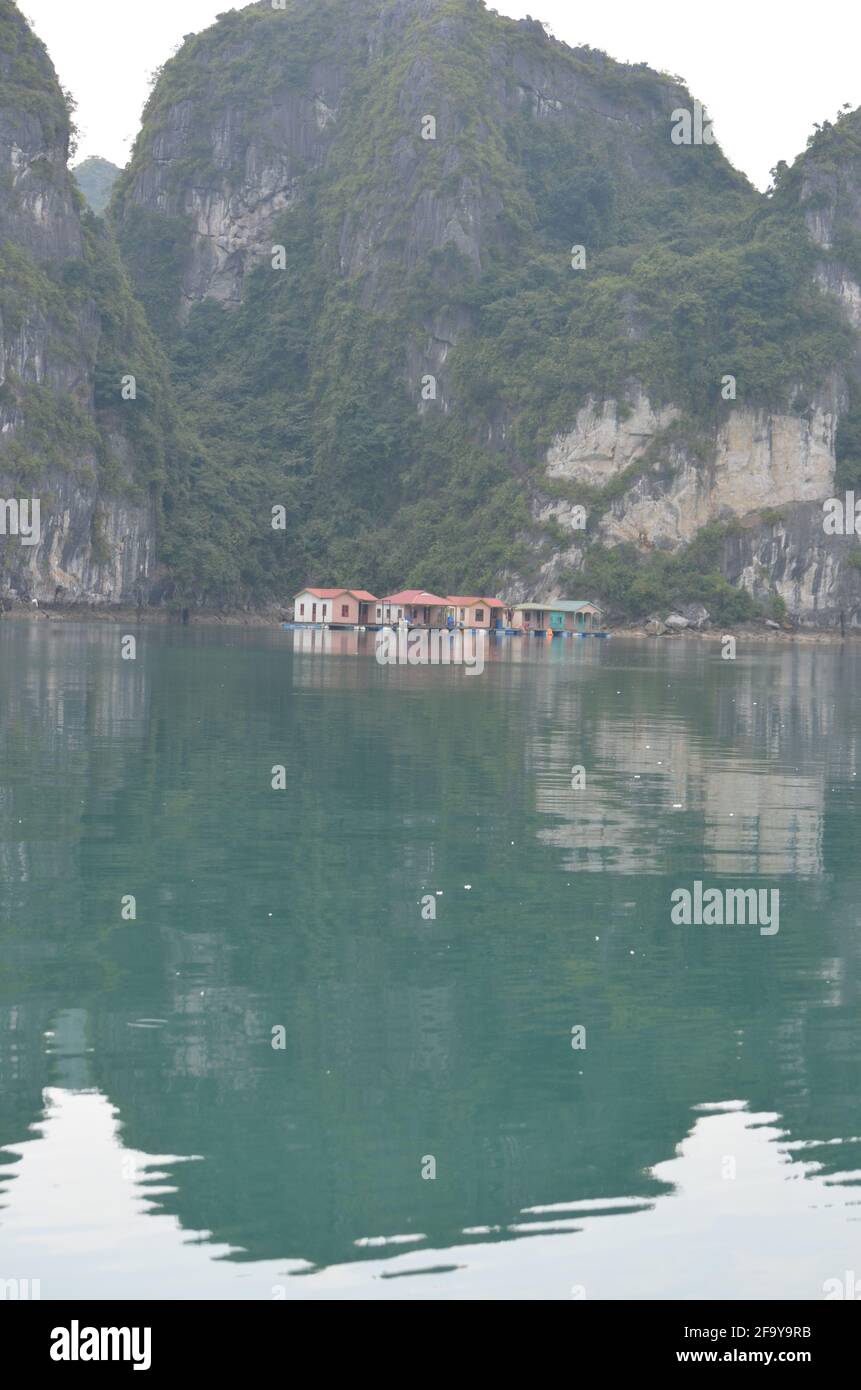Panoramic view of the green waters, the rock formations and the floating houses and boats on the Halong Bay in Vietnam Stock Photo