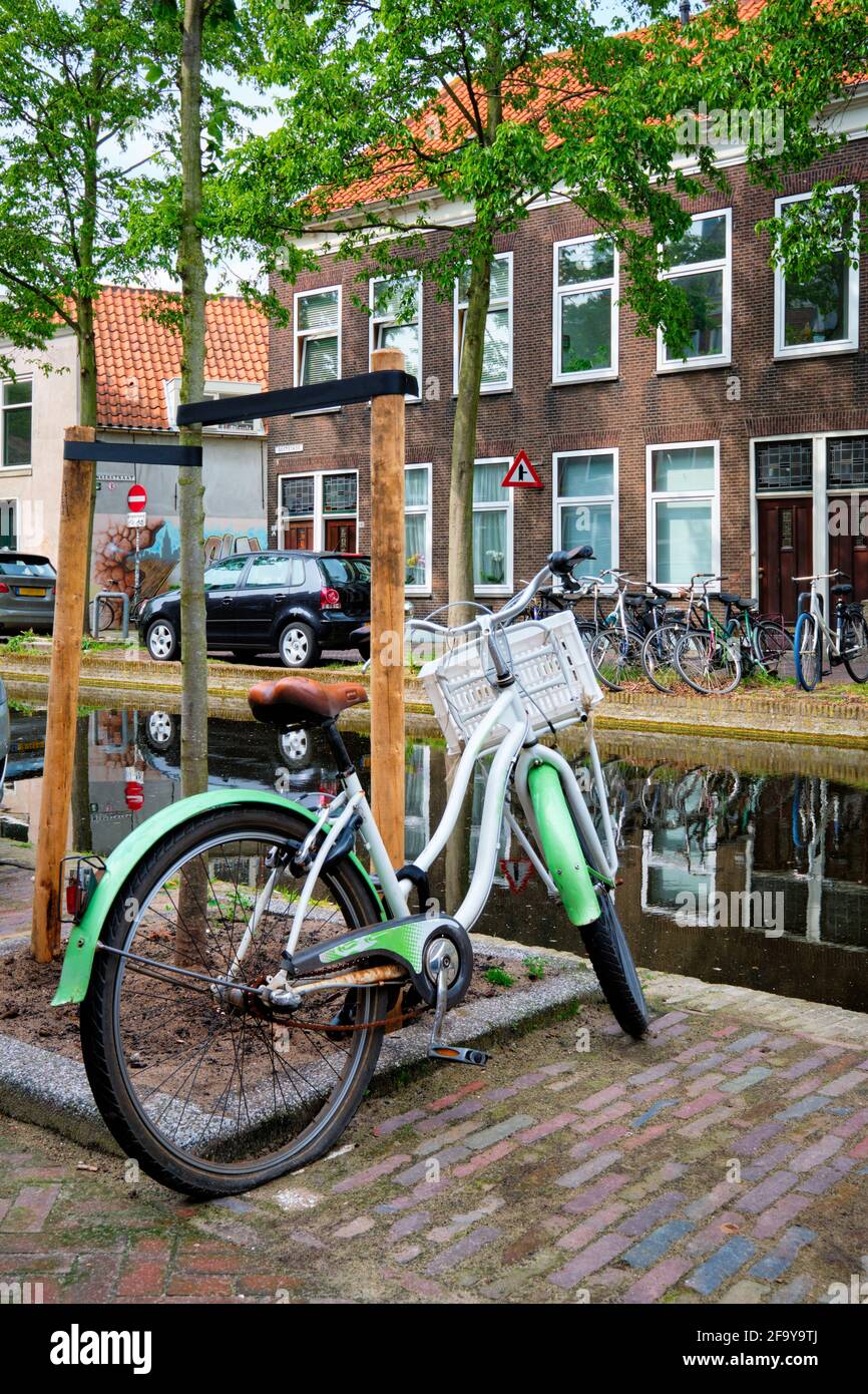 Bicycle parked near the canal in Delft street with old houses. Delft, Netherlands Stock Photo