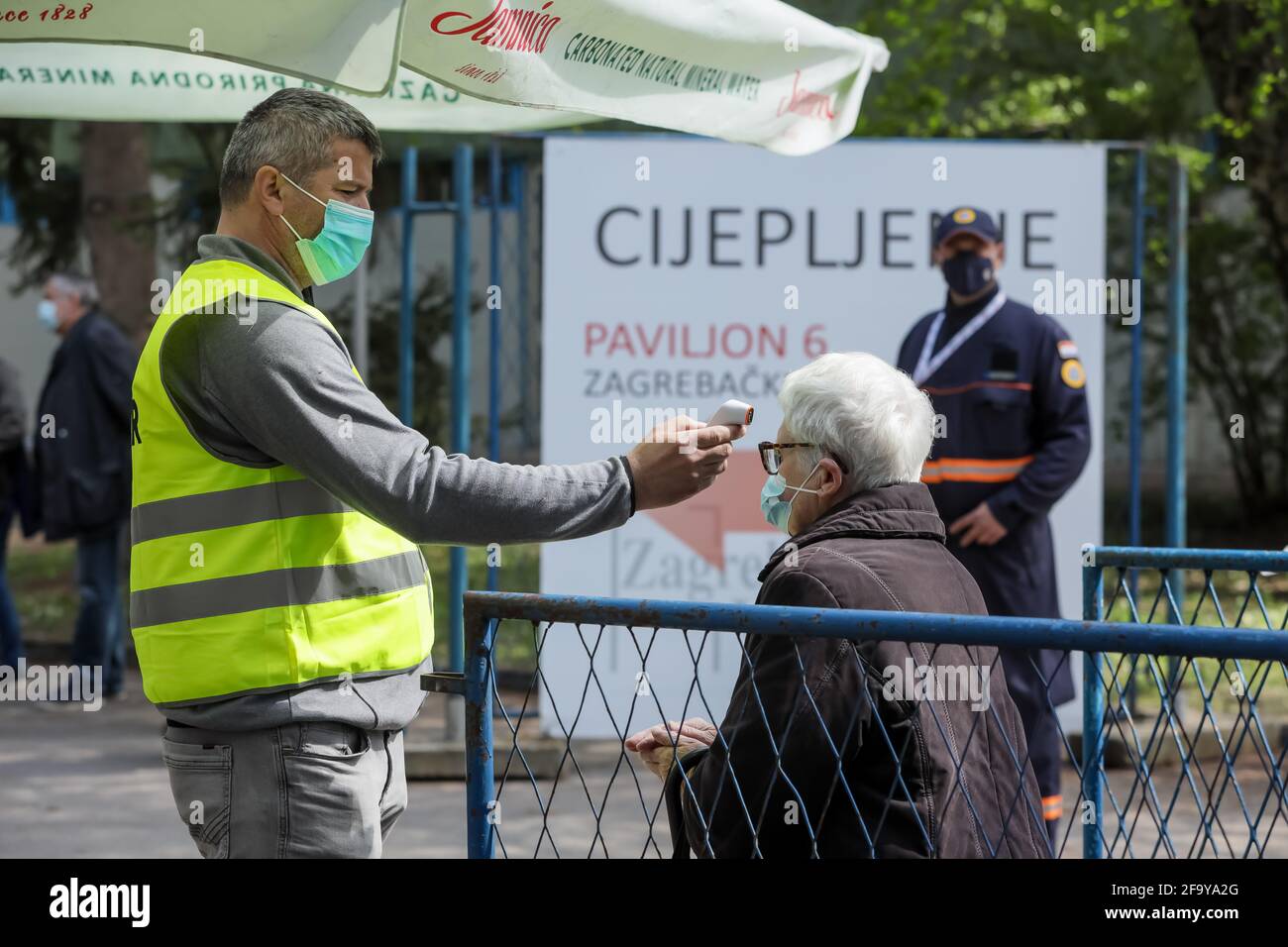 Zagreb, Croatia. 21th April 2021. Organized mass vaccination of citizens with the Pfizer vaccine  against Covid 19 virus in pavilion 6 of the Zagreb Fair. Covid guards measure the temperature of citizens before vaccination. Stock Photo