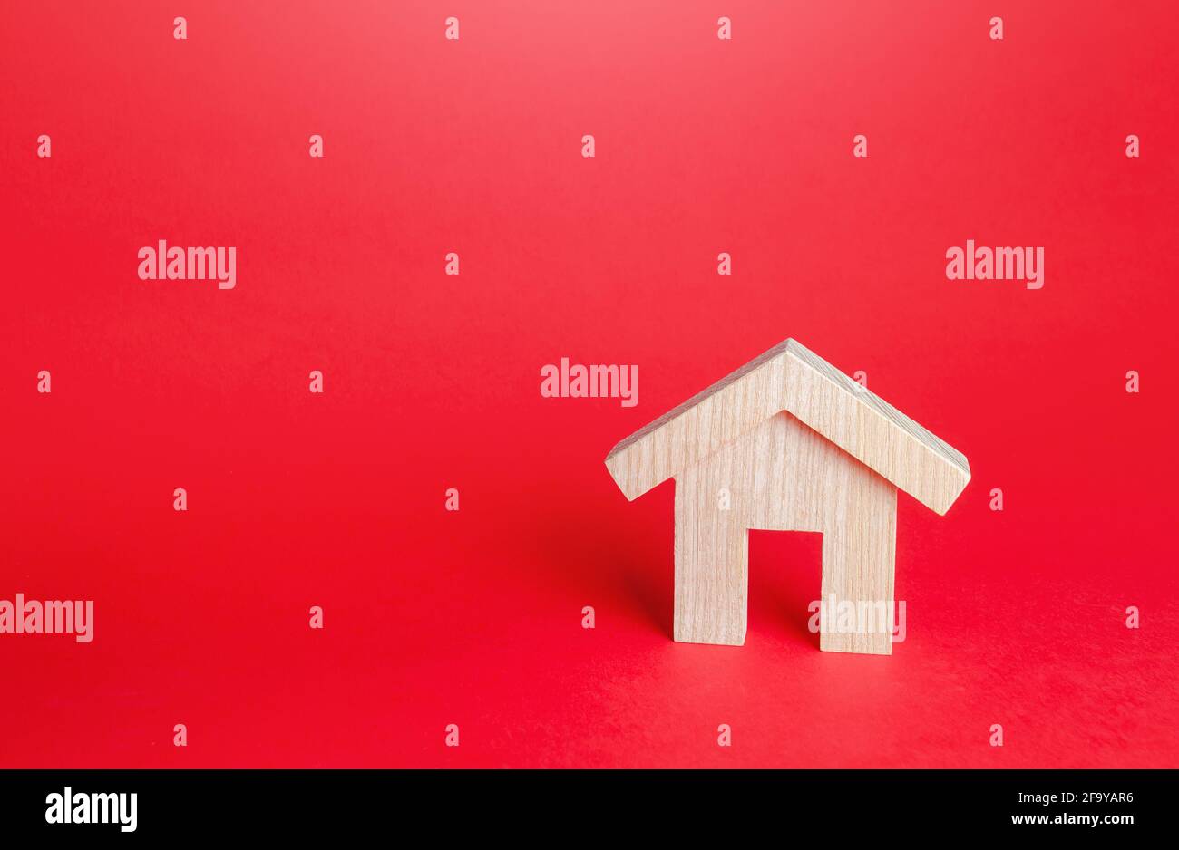Wooden house on a red background. Buying and selling. Housing, realtor services. Mortgage loan. Construction industry, building maintenance. Renovatio Stock Photo