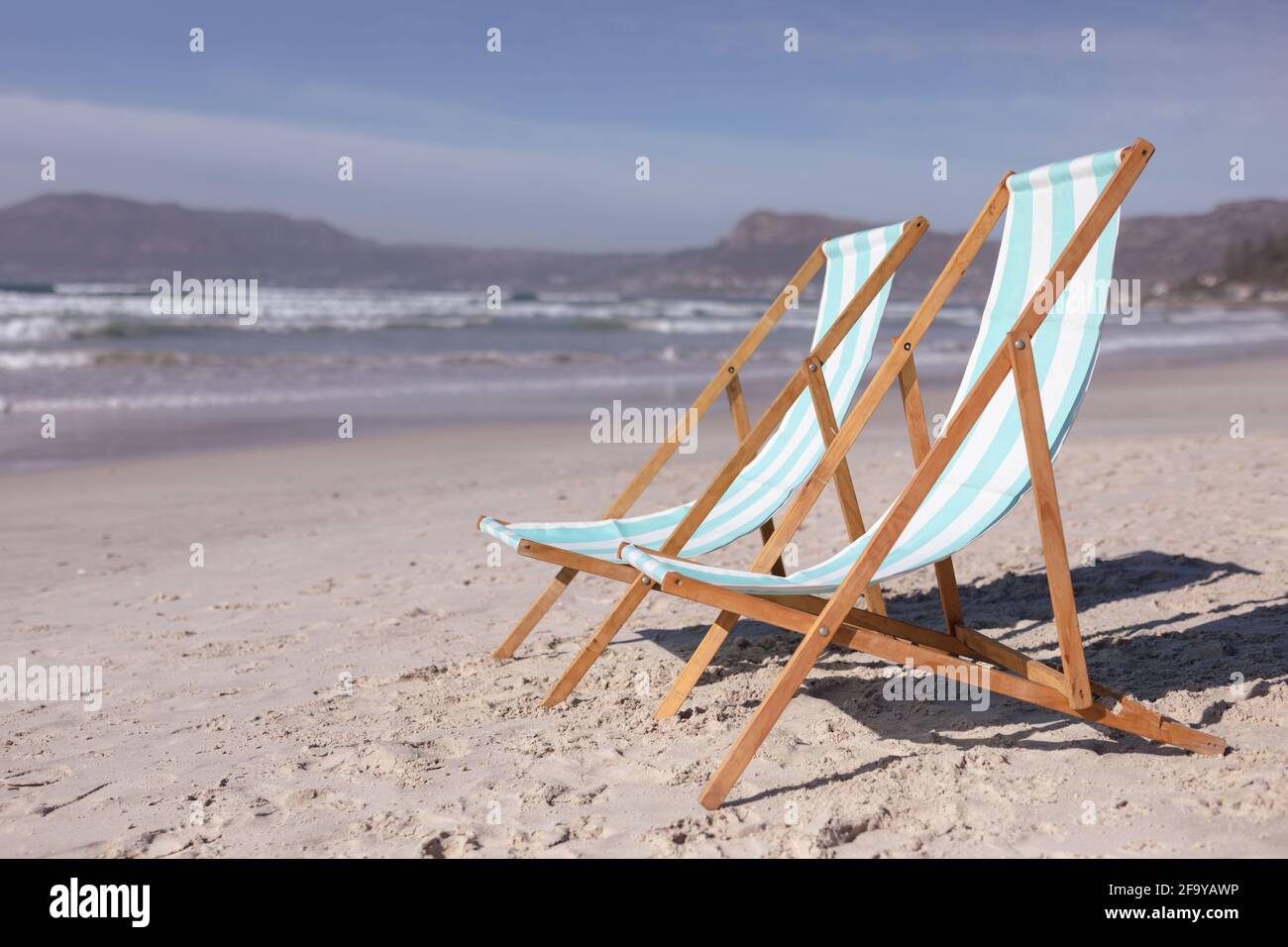 View of two deck chairs on the beach with sea waves Stock Photo - Alamy