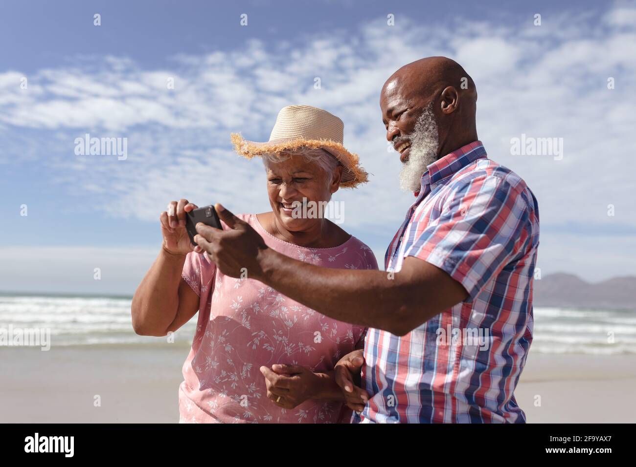 Happy senior african american couple using smartphone at the beach ...