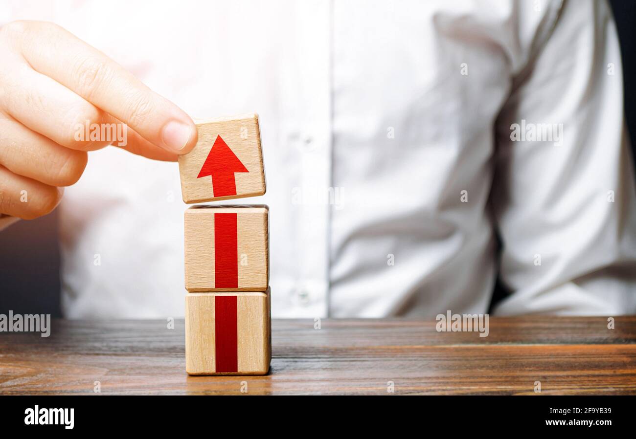 Man collects a tower of blocks with an arrow. Step-by-step career growth. Concept of development to new levels. Business expansion. Improving qualitie Stock Photo
