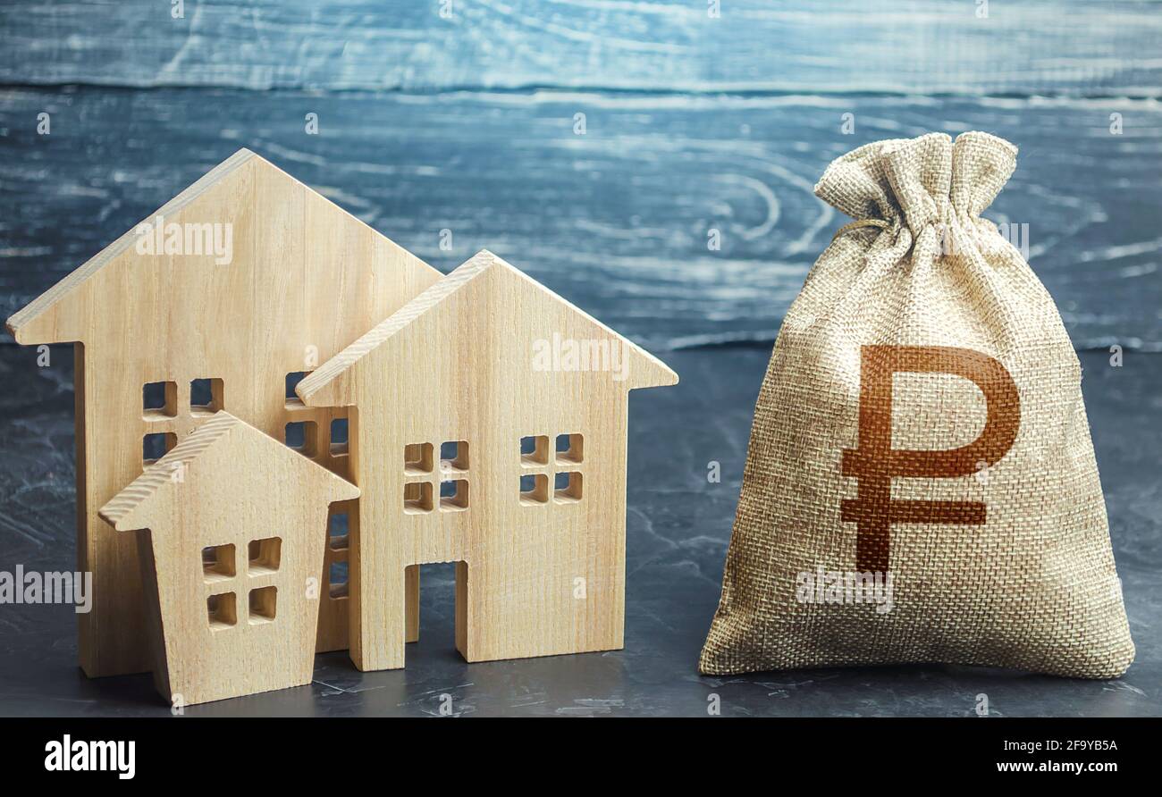 Russian ruble money bag and figurines of residential buildings. Property tax. Increase investment attractiveness. Financing urban development and infr Stock Photo