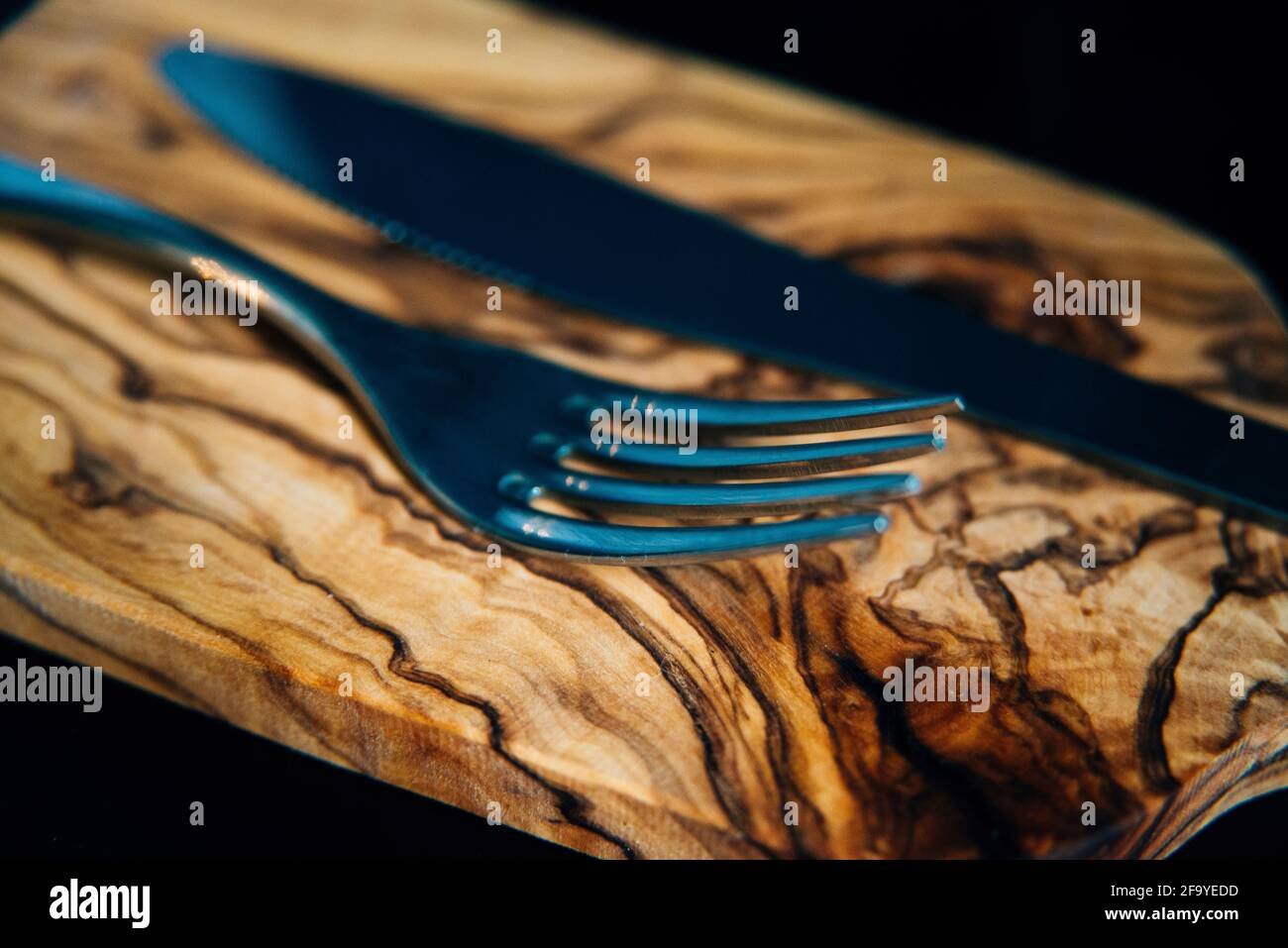 close up macro of a silver knife and fork on a bamboo wood choppig board Stock Photo