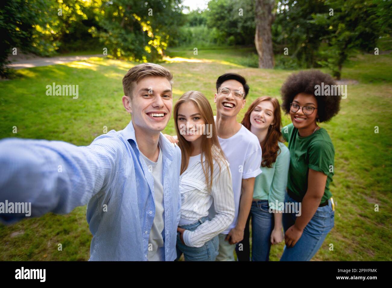 Group of multiethnical teen friends talking selfie outdoors in park Stock Photo