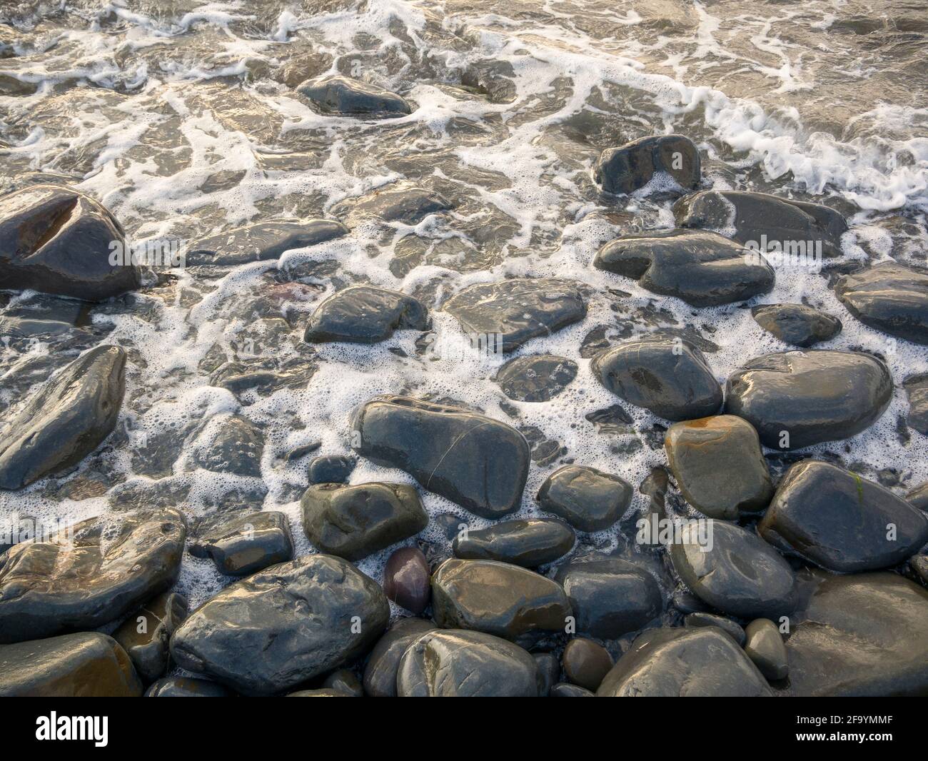 The sea washing up against wet pebbles on the shoreline. Stock Photo