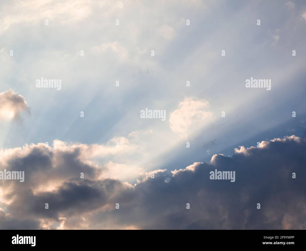 Crepuscular rays from the setting sun through clouds caused by particles in the atmosphere. Stock Photo