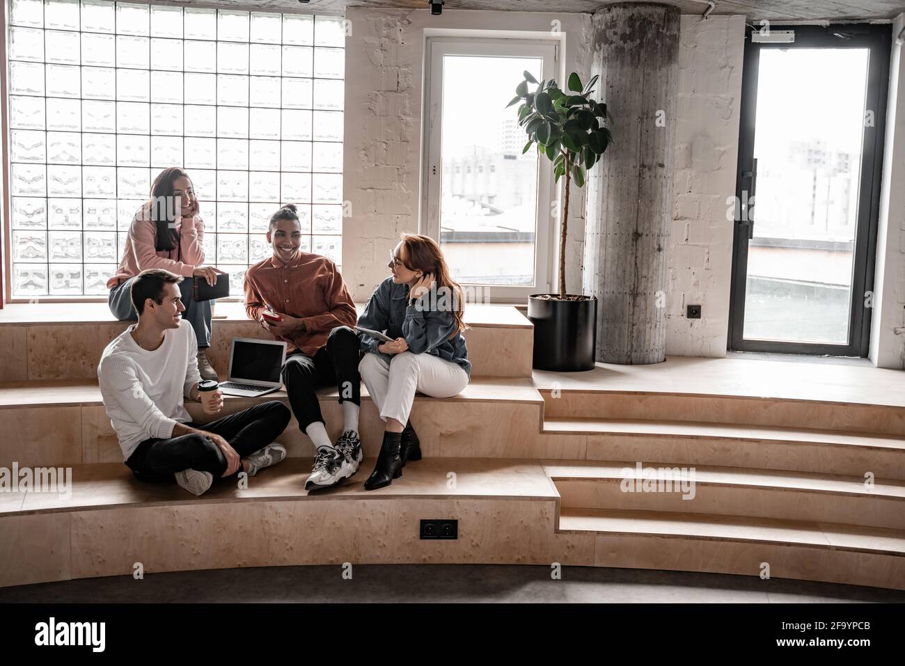 interracial students smiling while sitting on stairs Stock Photo