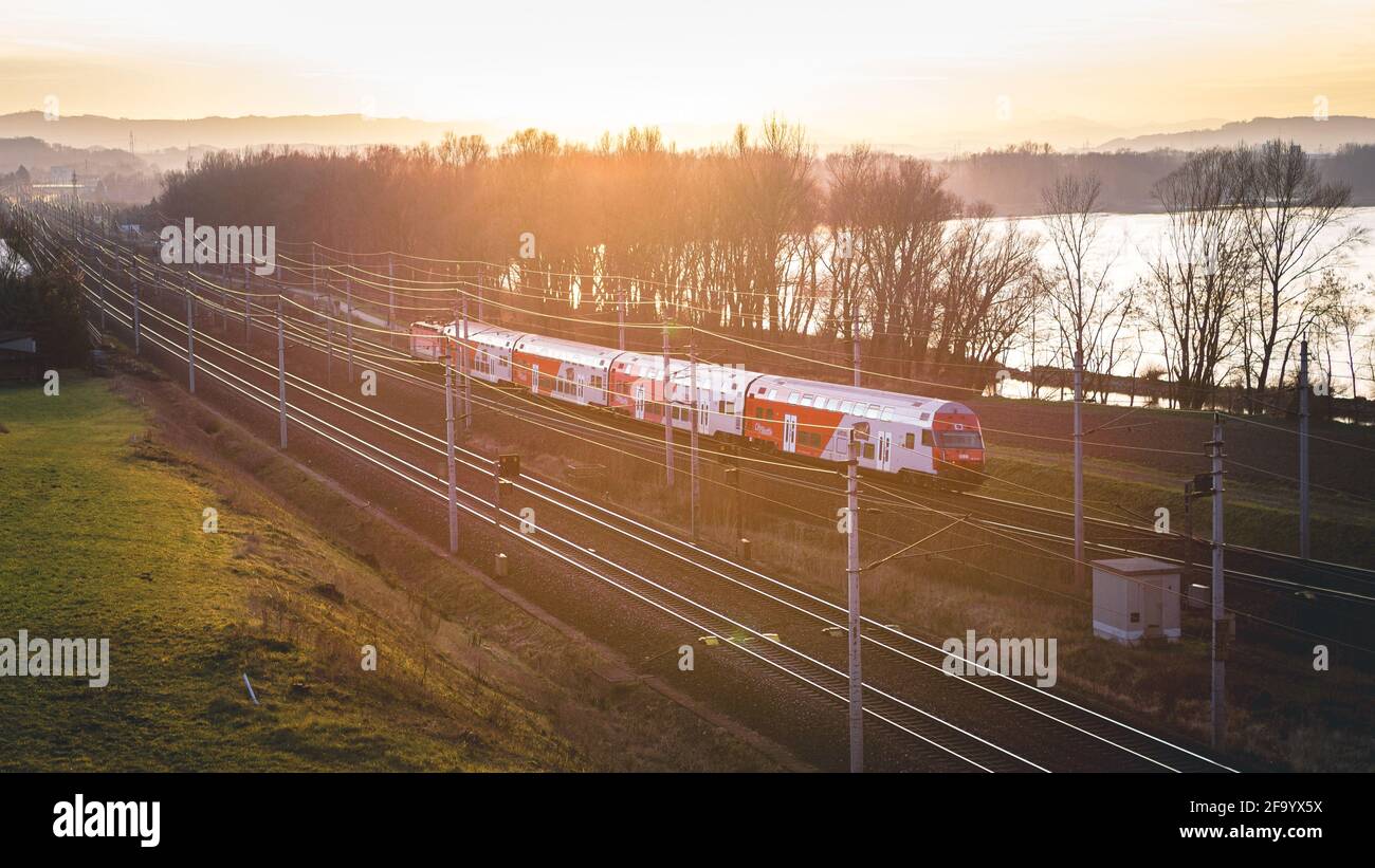 Train drive by in golden hour next to danube river, Lower Austria Stock Photo
