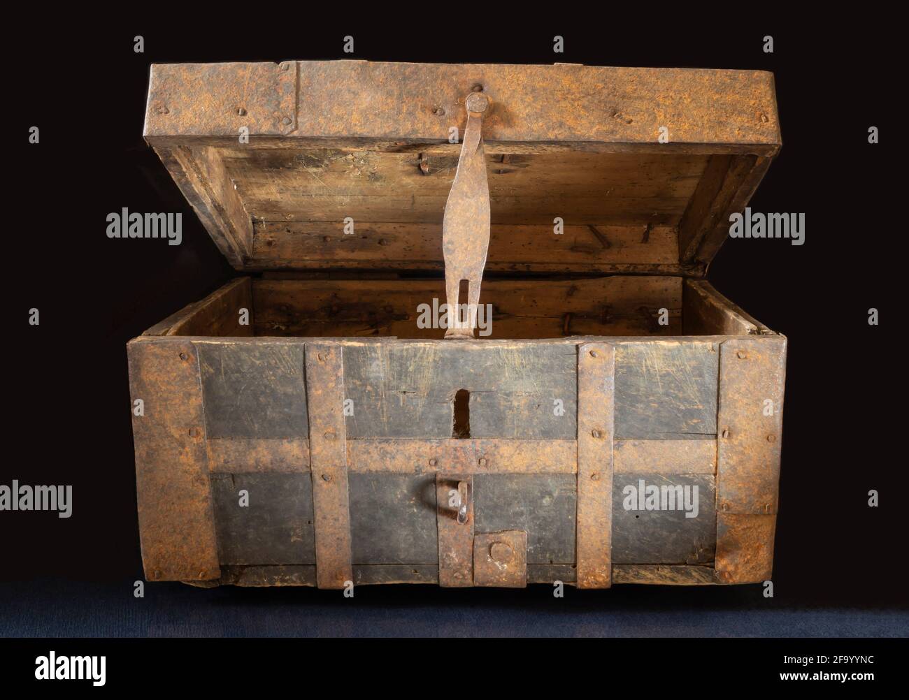 An old chest made of wood upholstered with iron. Open box on black background Stock Photo