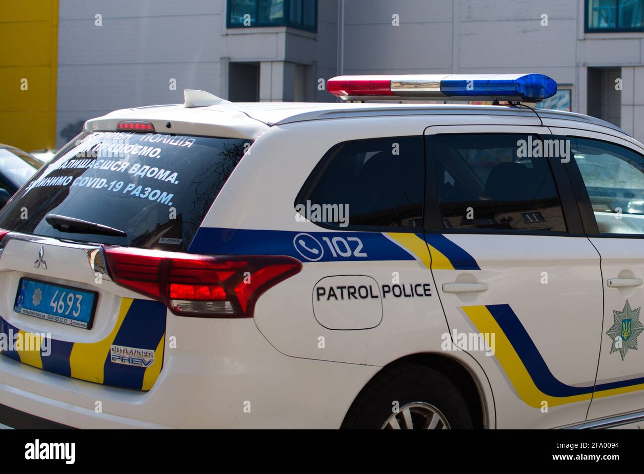 Patrol police car on city street. Stay at home. Let us stop COVID together on rear car window Stock Photo