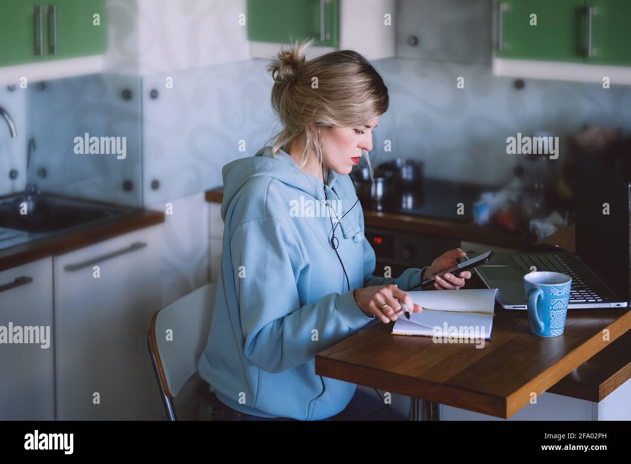 business woman looking at mobile phone while at home in the kitchen Stock Photo