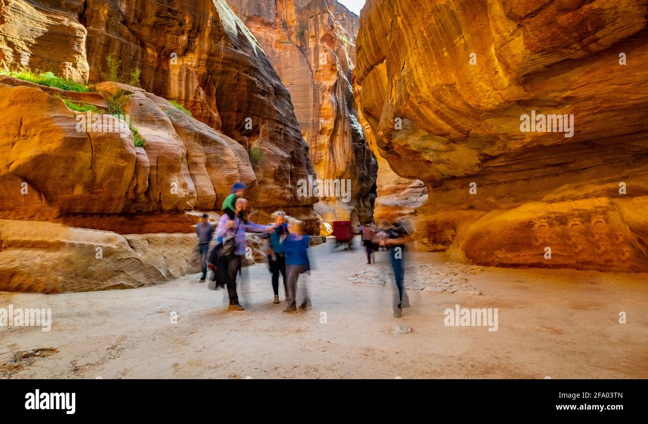 Group of people between sandstone rocks at narrow path in Petra, Jordan Stock Photo