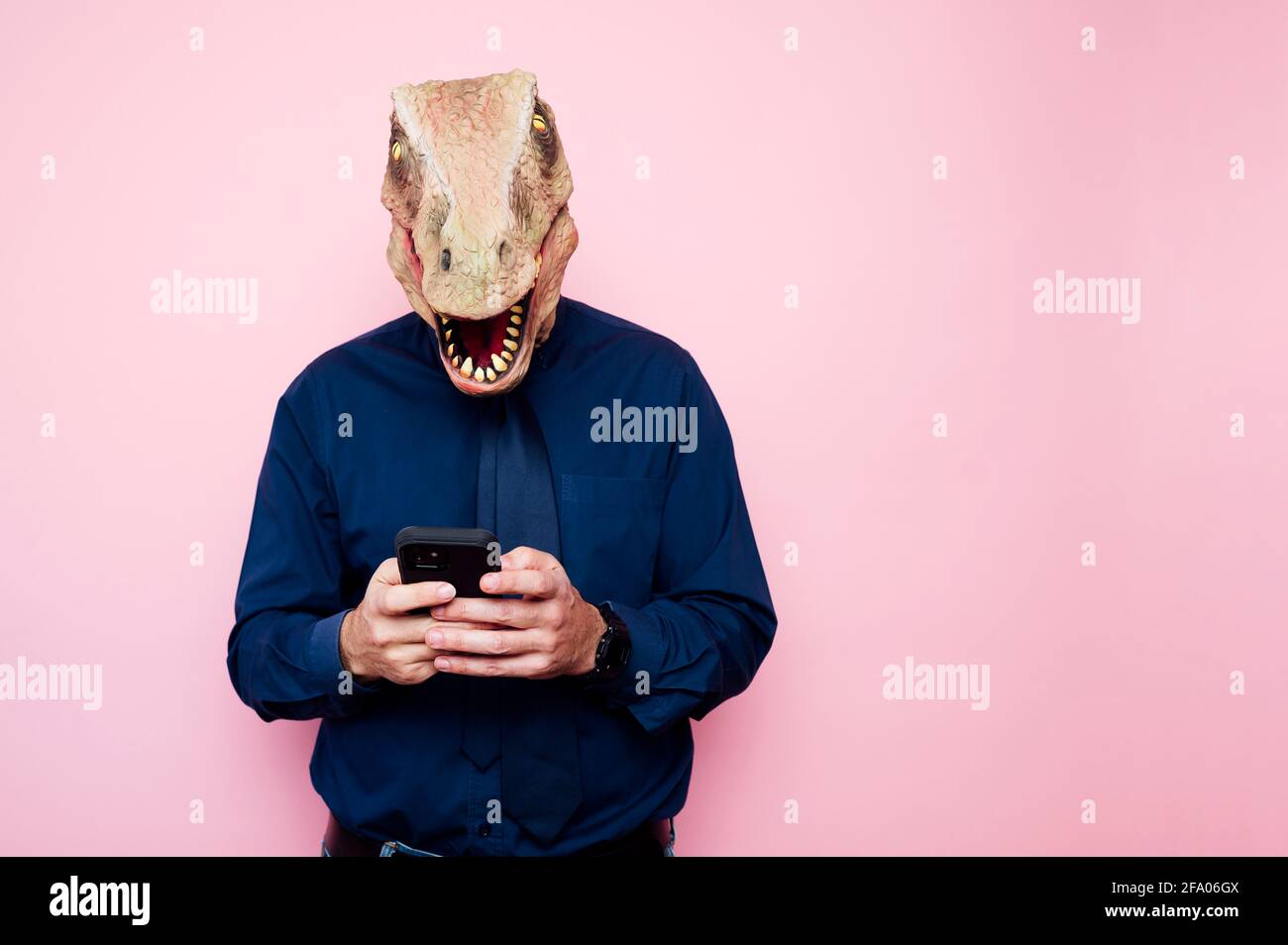 man in dinosaur mask using smartphone Stock Photo