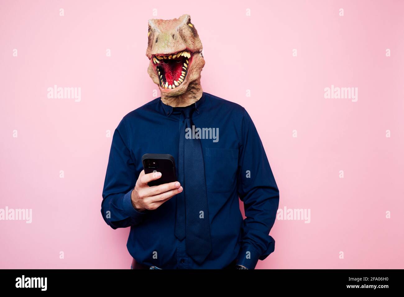 man in dinosaur mask using smartphone Stock Photo