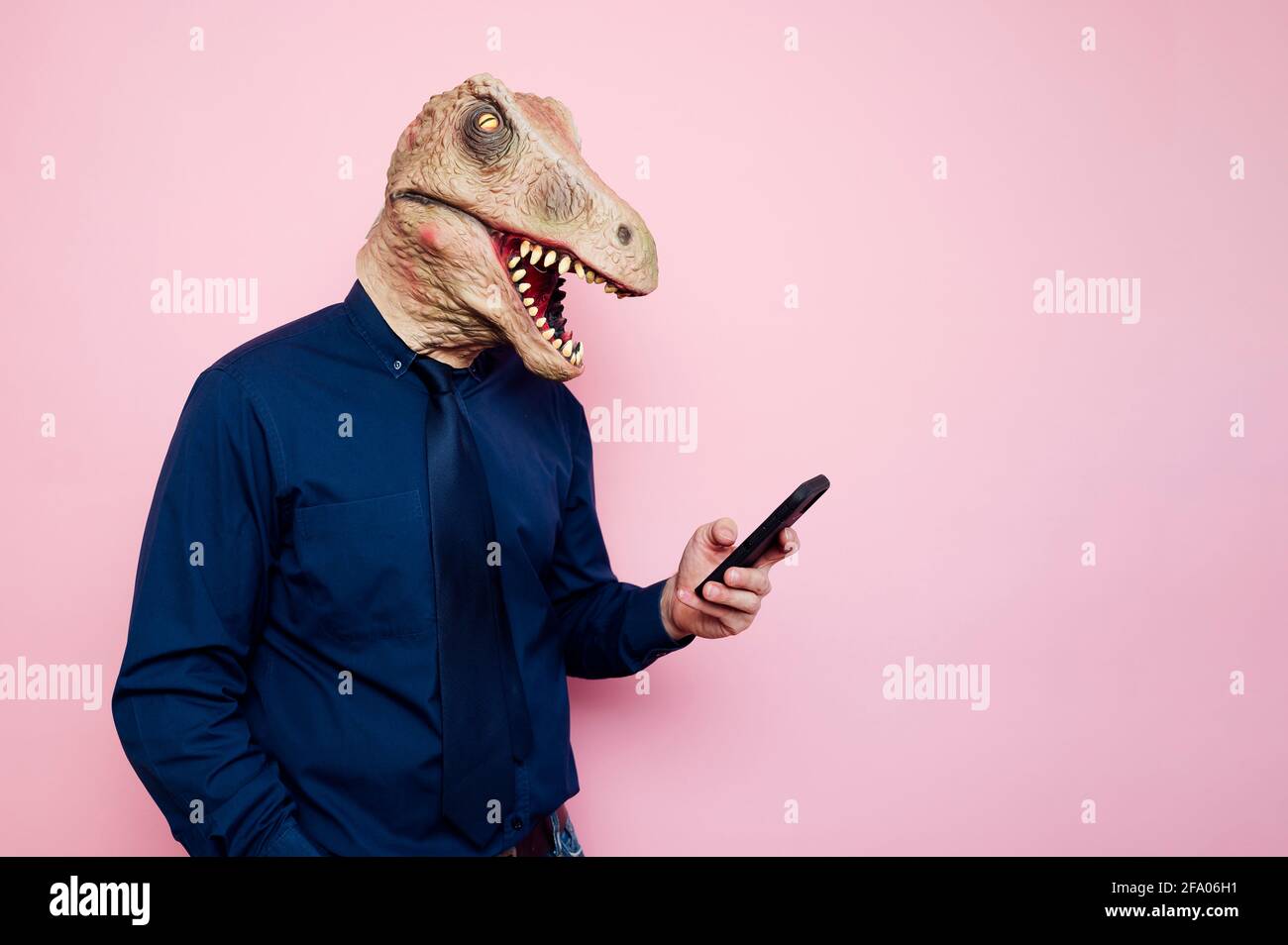 man in dinosaur mask using smartphone Stock Photo