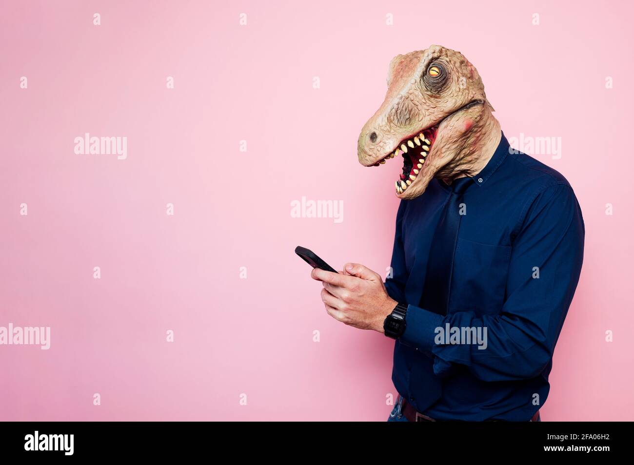 man in dinosaur mask using smartphone Stock Photo