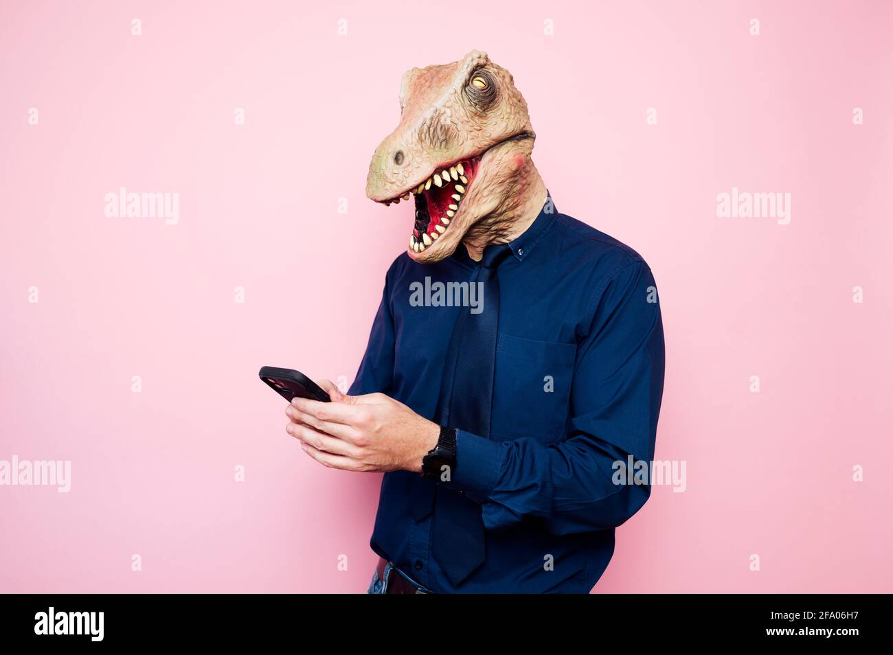 man in dinosaur mask using smartphone Stock Photo