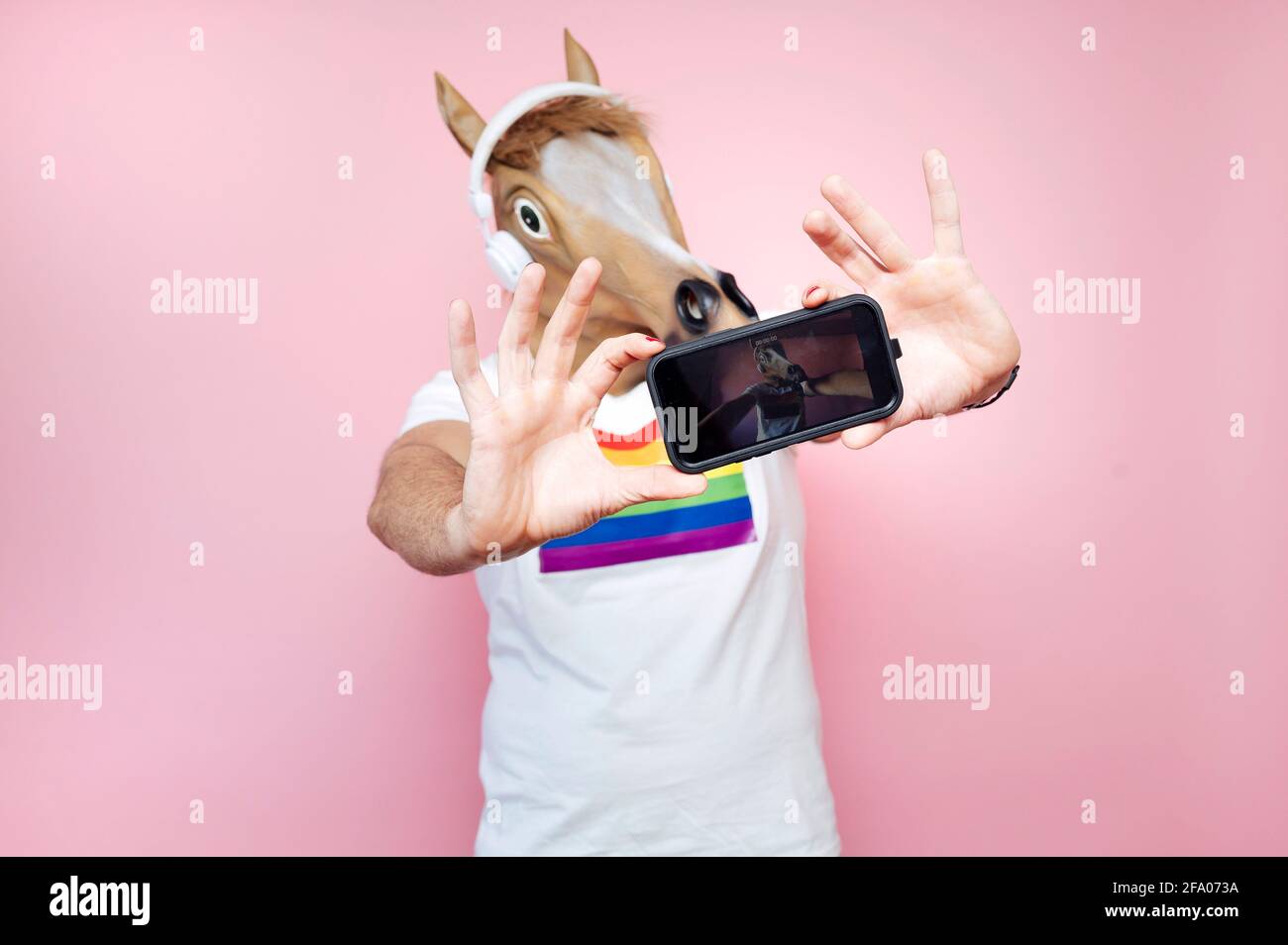 Man wearing horse mask while taking a selfie with smartphone Stock